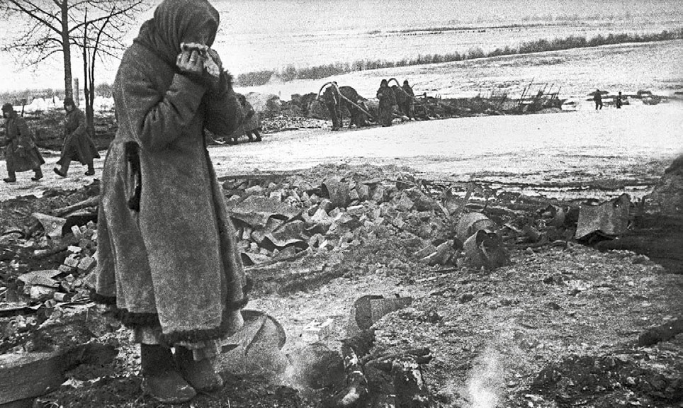 Пожилая жительница деревни у останков сгоревших родственников. 1943 г. 